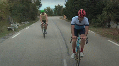two bicyclists are going down the road at dusk
