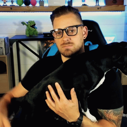 man wearing glasses is holding his dog in his arms