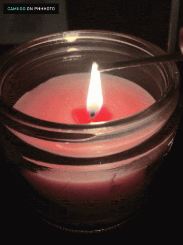 a candle glowing in the middle of a glass jar