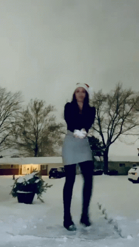 a woman standing in the snow wearing a skirt