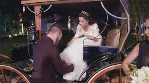 a bride is sitting in a carriage in the daytime