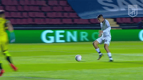 a soccer player kicking a soccer ball on an indoor field