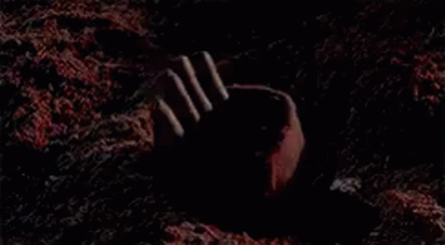 dark image of a person's hand reaching out from the ground