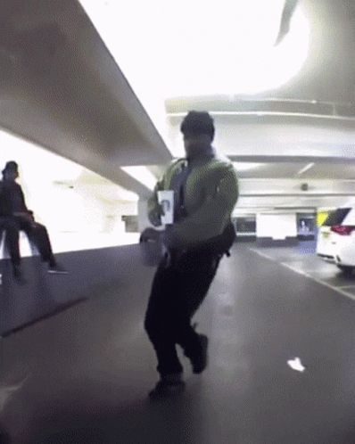 a man wearing all black walking through an airport with no one in his uniform
