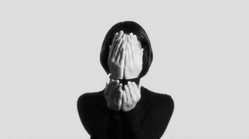 a woman in black shirt covering her face with hands