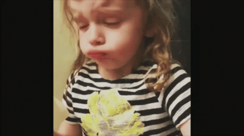 a toddler eating soing and wearing a striped shirt