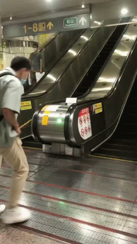 a guy stands on his skateboard while hing an escalator