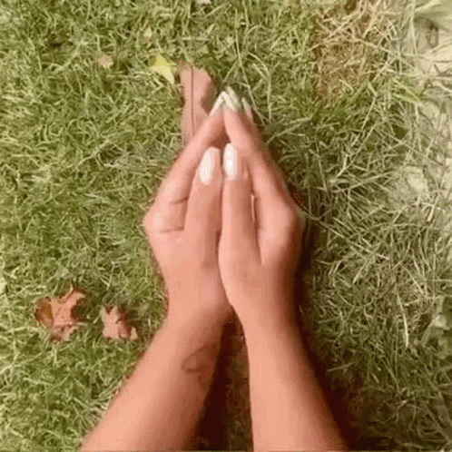 a person sitting on the ground and holding their hands together