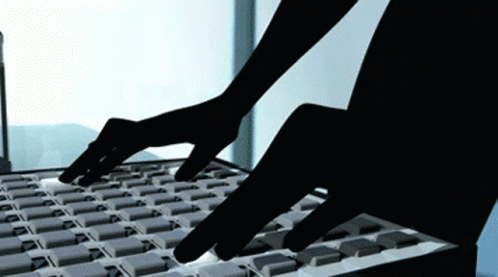 silhouette of hands typing on keyboard that is gray
