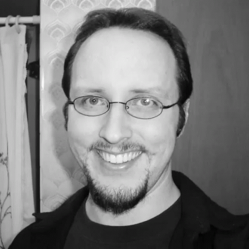 man with glasses and black shirt posing for the camera