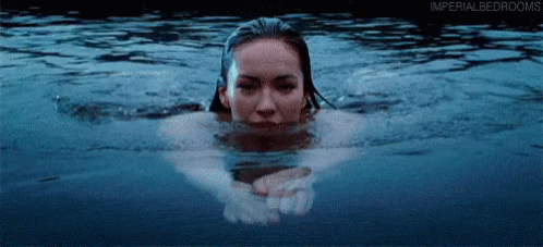 a woman floating in water looking at her reflection