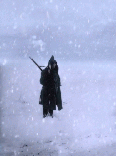 a man walking in the snow with a hunting pole