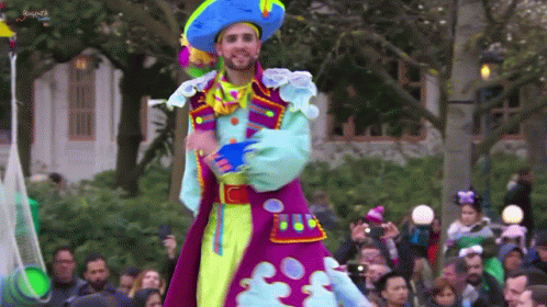 a man dressed up in colorful clothing at an outdoor event