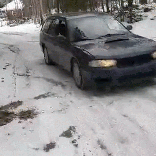 a car driving down a snowy road next to trees