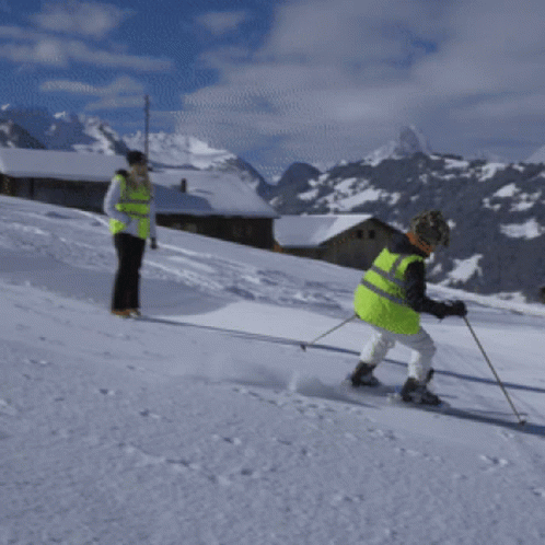 two men in green jackets ski on the slopes
