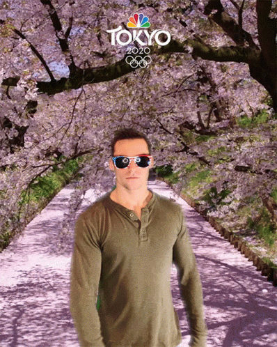 a man standing on a path in front of pink blossom trees