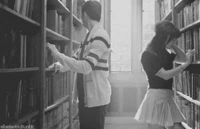 two people are searching for books in a liry
