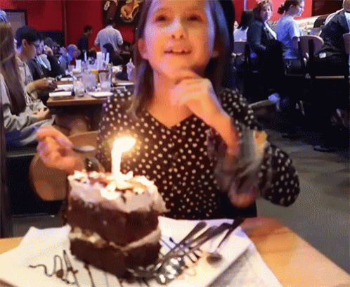 a young woman eating a piece of birthday cake