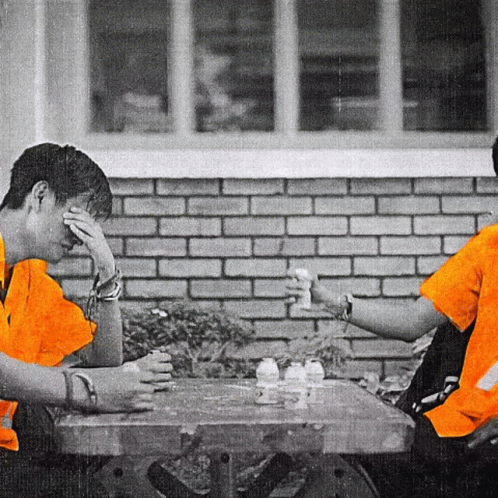 two girls sitting at a table outside playing chess