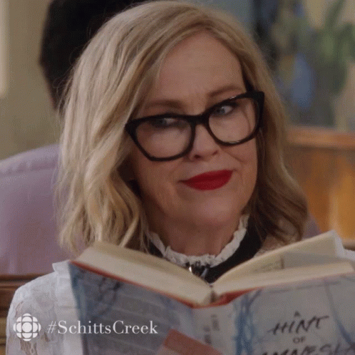 a woman wearing black eyeglasses reads a book