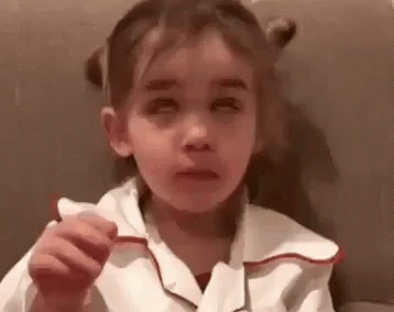 a little girl wearing a white shirt holds her finger in a weird manner