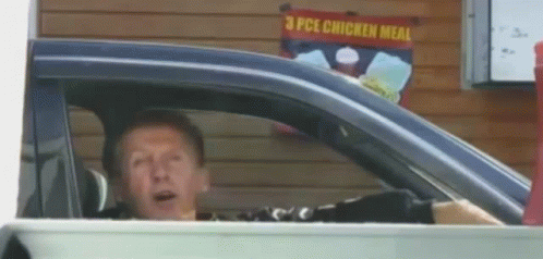 a man sitting in a car with a surprised look on his face
