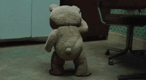 there is a gray teddy bear standing in the corner