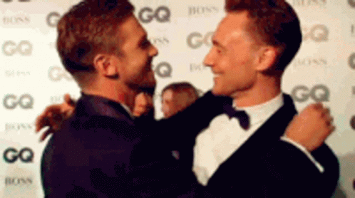 two men standing on the red carpet looking at each other