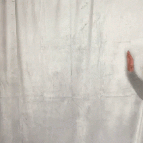 a man leaning up against a white curtain
