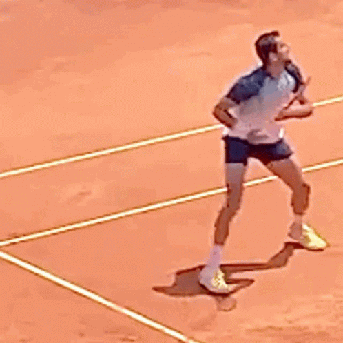 a woman walking across a tennis court holding a racquet