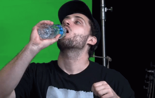 a man eating a sandwich while drinking some liquid