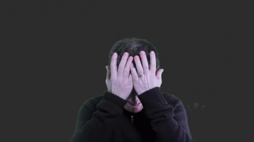 person covering their face with hands in the dark