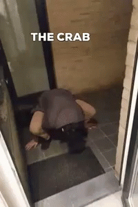 man bending down outside a door to pick soing out