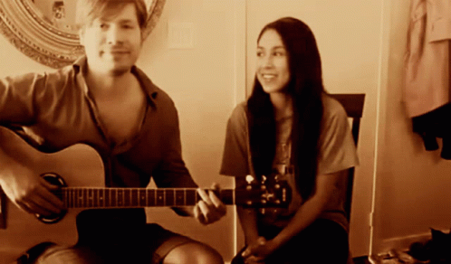 a young man and a young woman playing guitars
