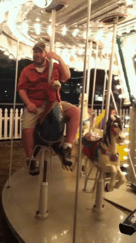 a man rides a merry go round with several people