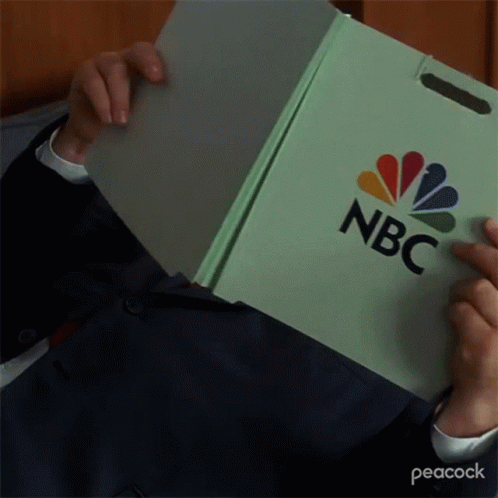 a person in a suit holds an nbc box