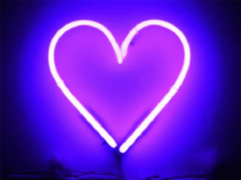 a close up of a neon pink heart in the dark
