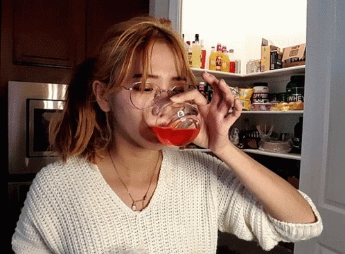 a woman in glasses drinking soing blue