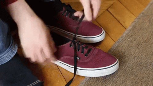 person putting on purple vans shoes and tieing