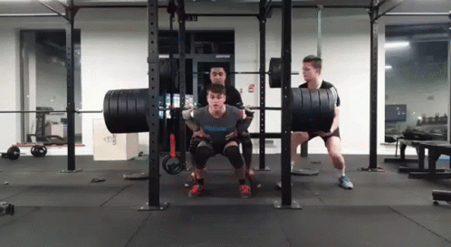 two men performing squats on a weight rack