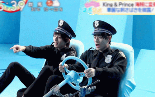 two asian police officers sitting down and one pointing at soing