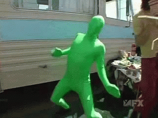 a creepy green dummy walking towards a person in front of a trailer