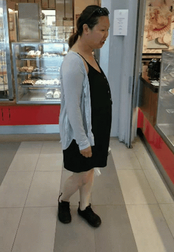 a woman is standing in front of a bakery display case