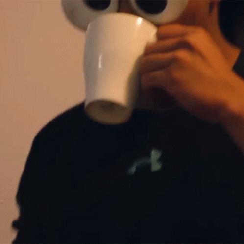 someone drinking from a coffee cup while wearing a fake eyeball head