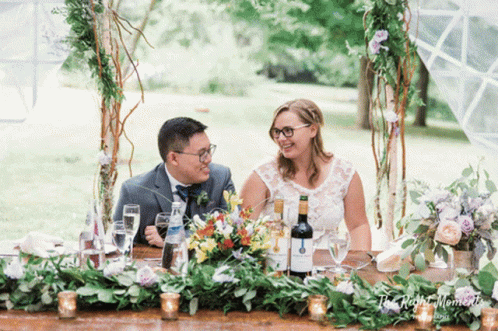 the couple is at a table with flowers and bottles