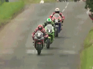 three motorcycles are driving on a road with two of them going behind them
