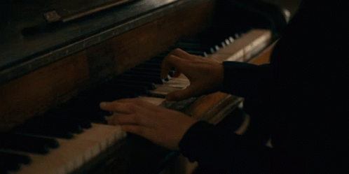 a person is playing the piano while another looks on