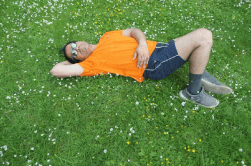 a young man lying on top of a green field