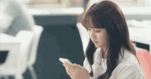 a girl sitting in a chair holding a cellphone