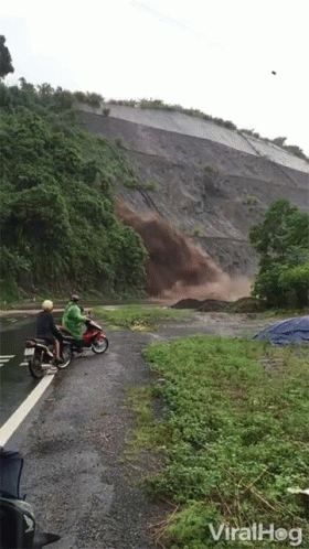 two people riding a motorcycle down a dirt road